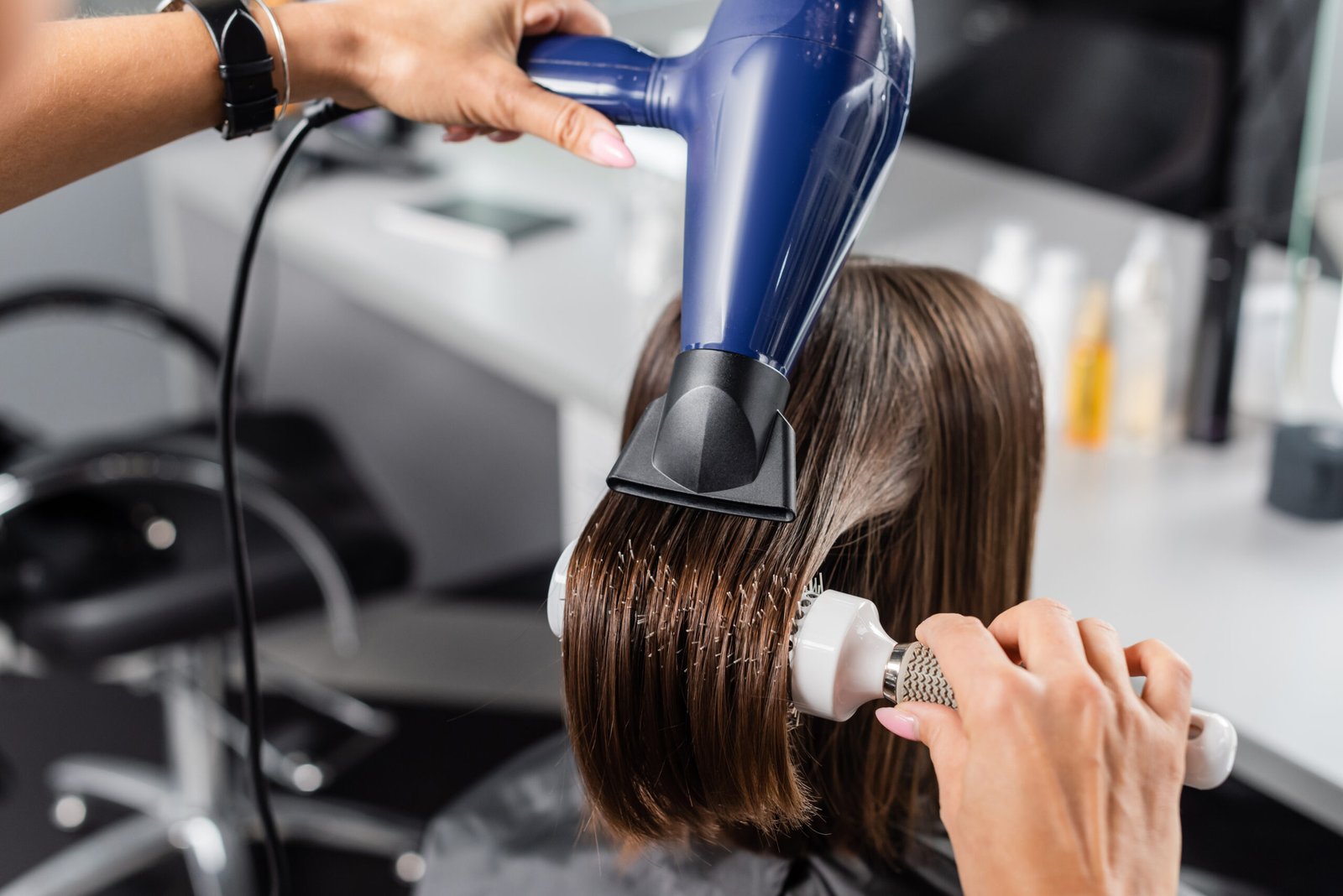 A woman at a salon getting her short bob haircut blow dried, demonstrating the use of blow drying for styling.