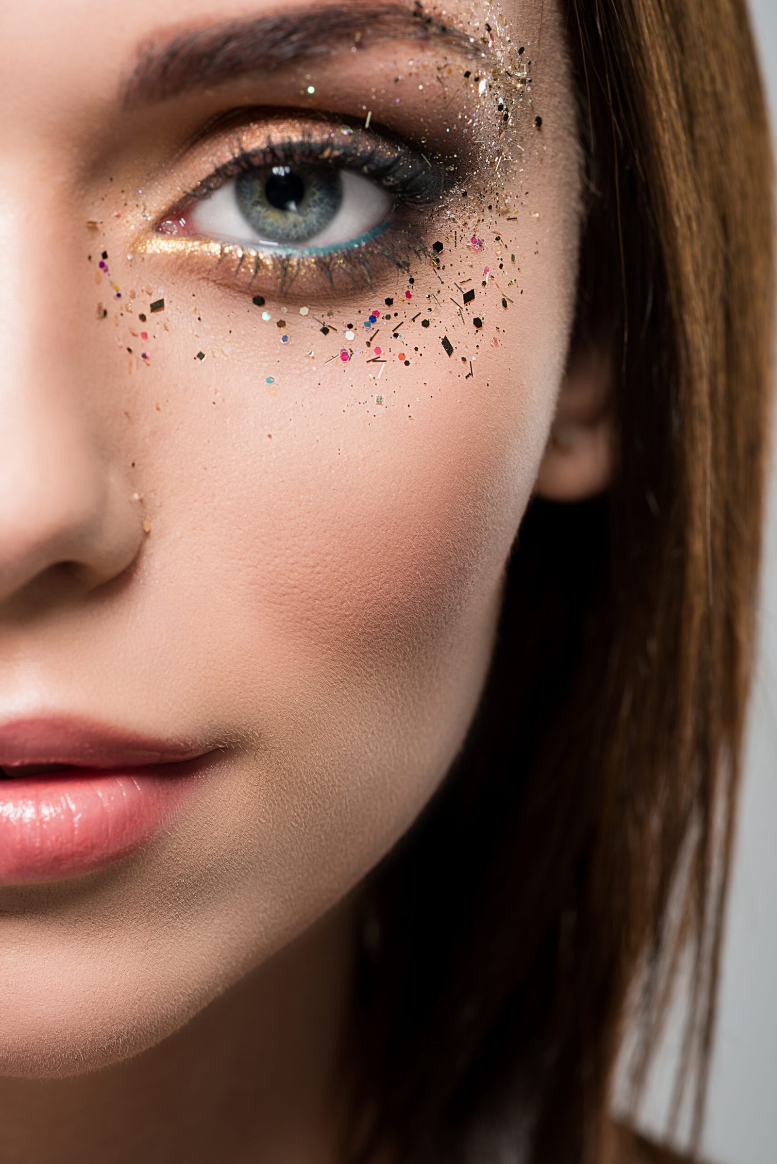 A glamorous woman adorned with shimmering glitter on her face, showcasing stunning party makeup highlights.