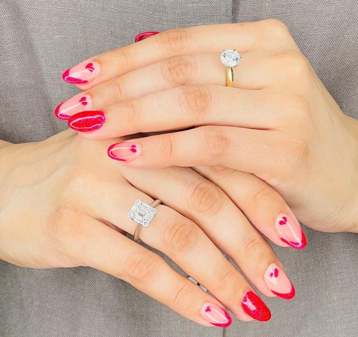 A woman displays her stylish, glossy red and pink nails, emphasizing her chic nail extensions.