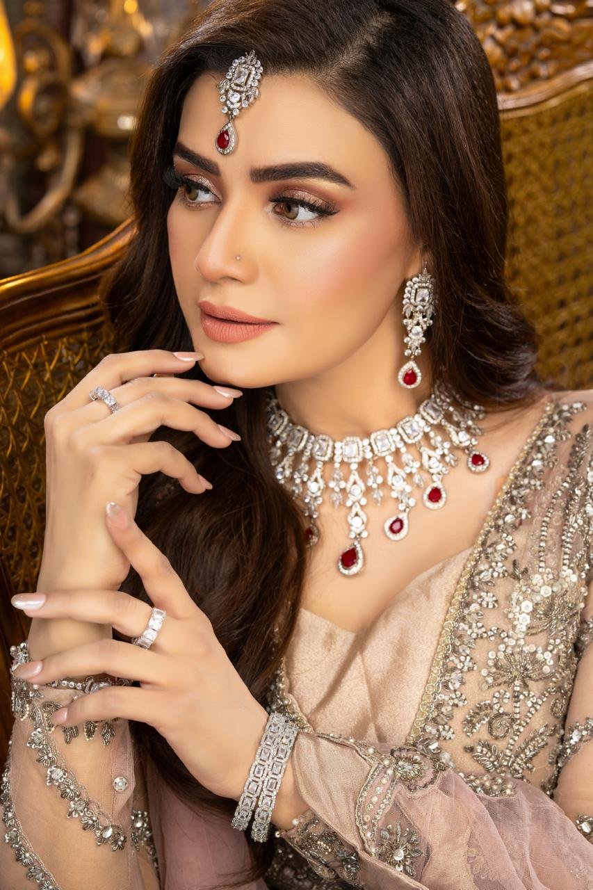 Kiran Haq poses a stunning bride adorned in traditional jewelry, showcasing exquisite Valima makeup, radiating elegance.