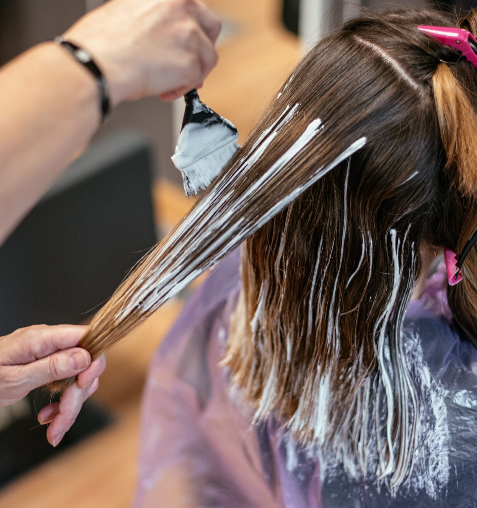 A woman enjoys exquisite hair highlights at Skinfinity, pampered by a skilled specialist in a luxurious salon setting.