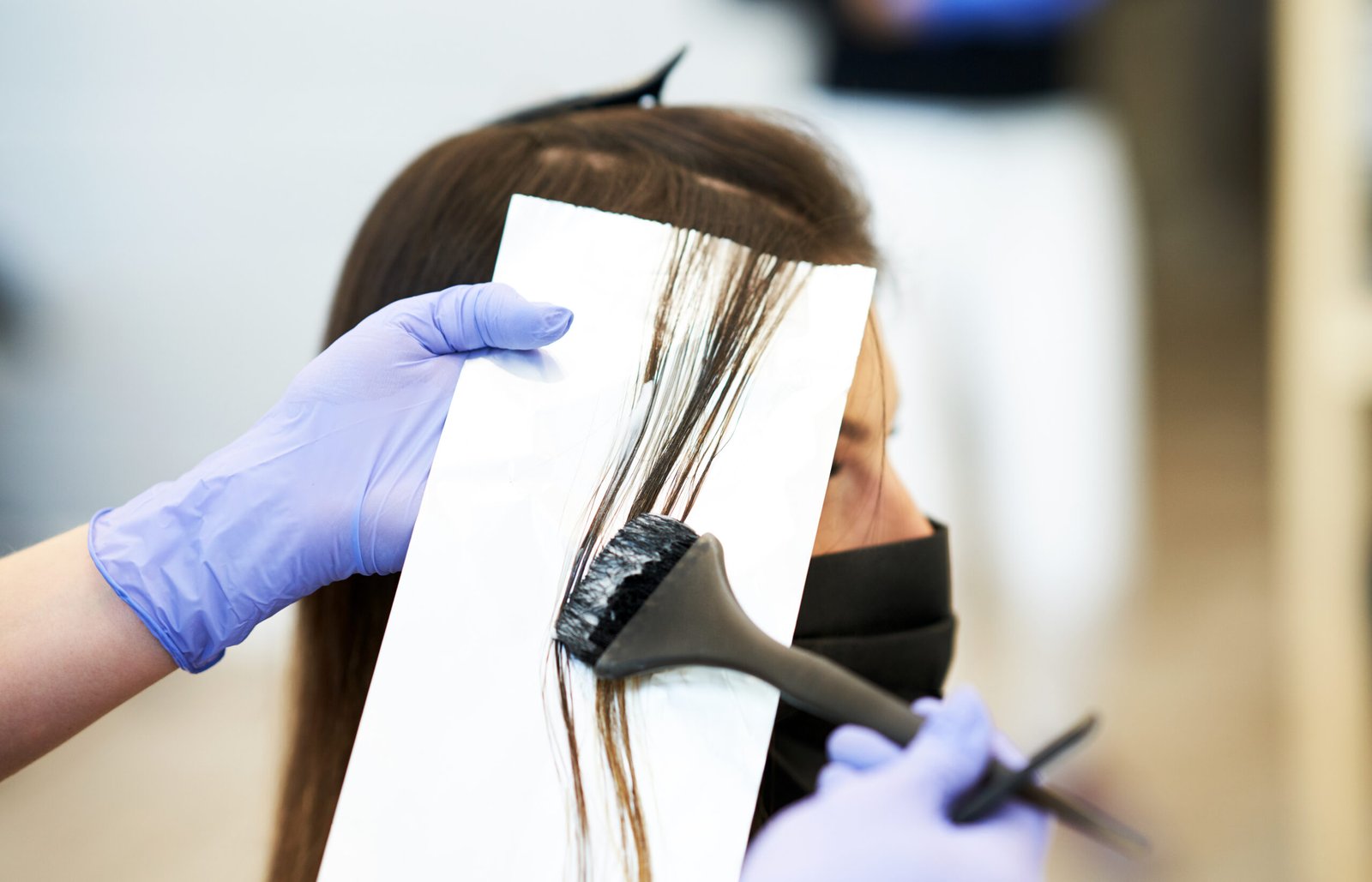 A woman enjoys a luxurious hair styling session, getting her hair brushed elegantly to coloring perfection.