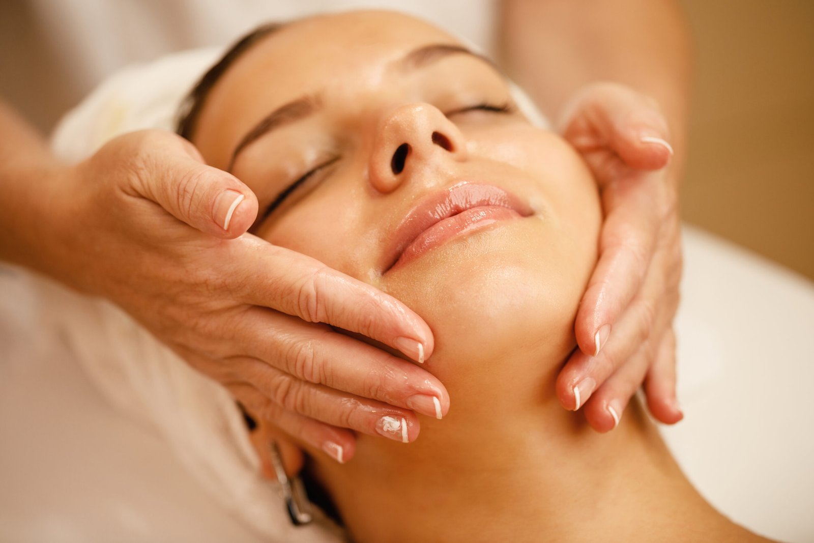 A woman enjoys a soothing facial massage, enveloped in elegance and relaxation, embodying the essence of self-care.