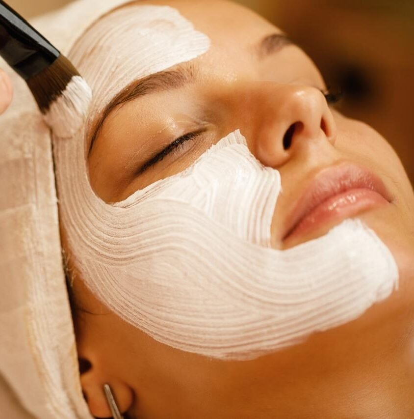 A woman enjoys a luxurious facial mask treatment at a tranquil spa, embodying relaxation and self-care in a serene setting.