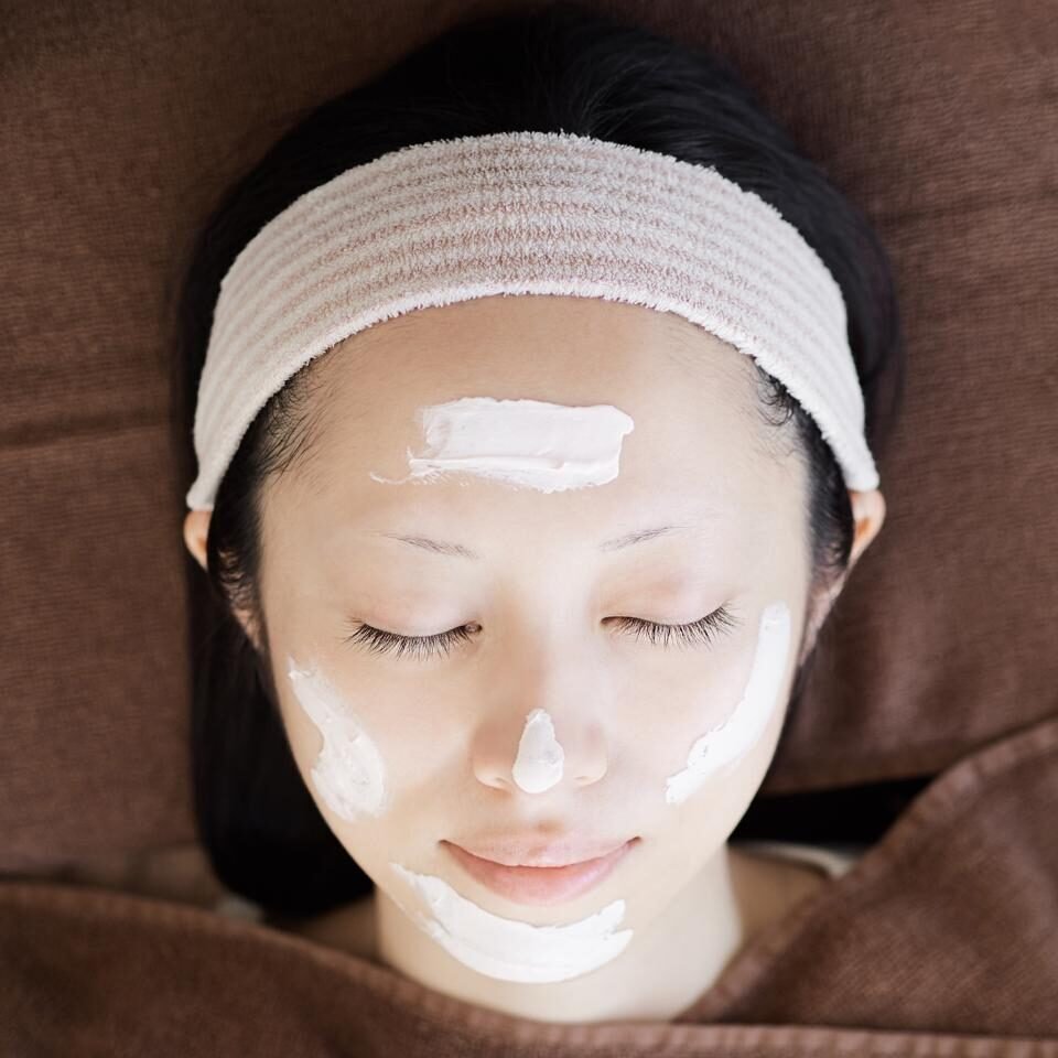 A serene woman relaxing, covered head, indulging in a luxurious spa facial, embodying pure relaxation.