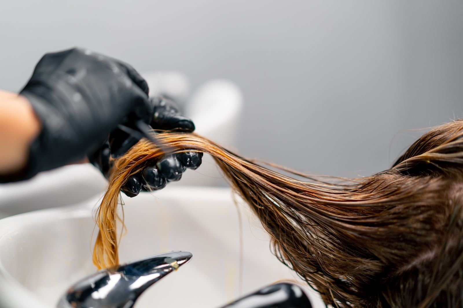 A woman receives sophisticated hairstyling in a lavish salon, highlighting the beauty of transformation and expert craftsmanship.