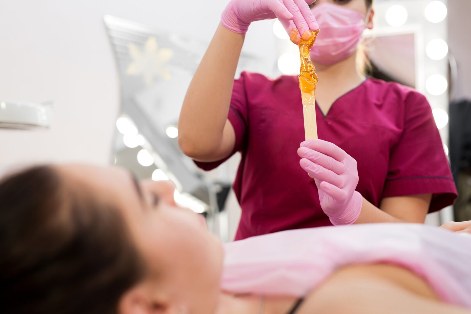 In a chic salon, a woman receives a honey wax treatment, indulging in a moment of pampering and self-care.