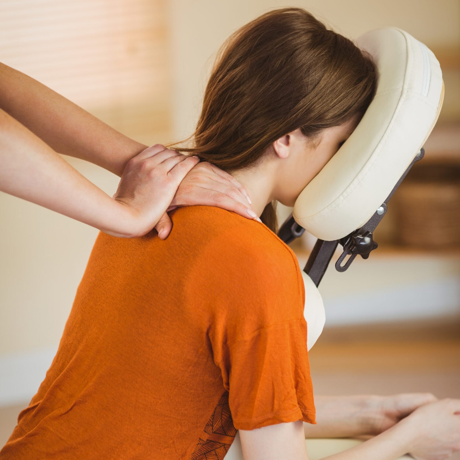 A woman relaxes in a massage chair, enjoying a soothing shoulder massage to ease her tension and stress.
