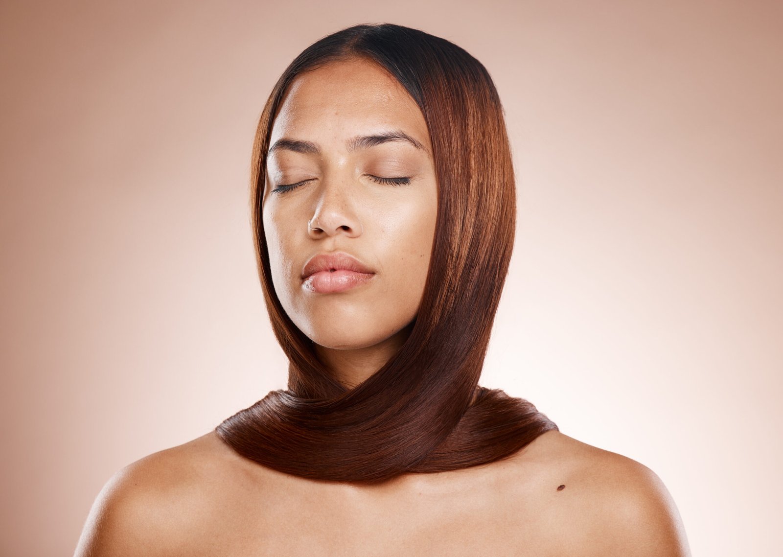 A woman with her eyes closed and hair styled in an updo, reflecting the effects of a keratin treatment.