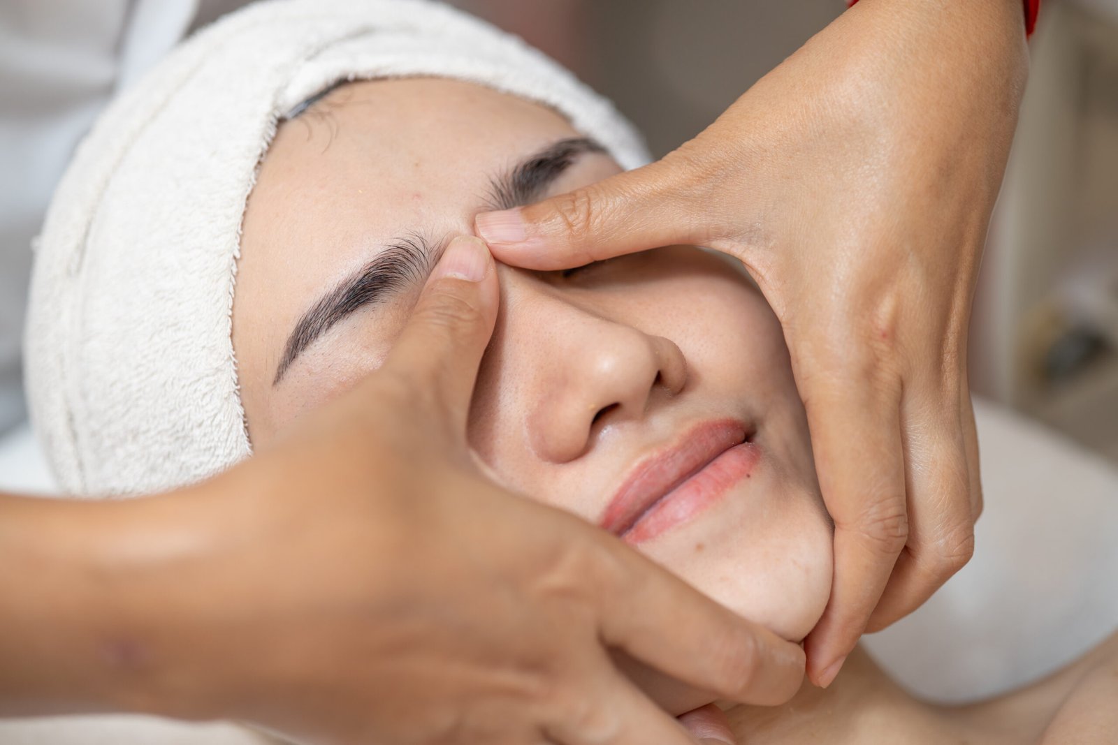 Woman receiving brightening facial massage at a luxury salon, enhancing skin glow and relaxation