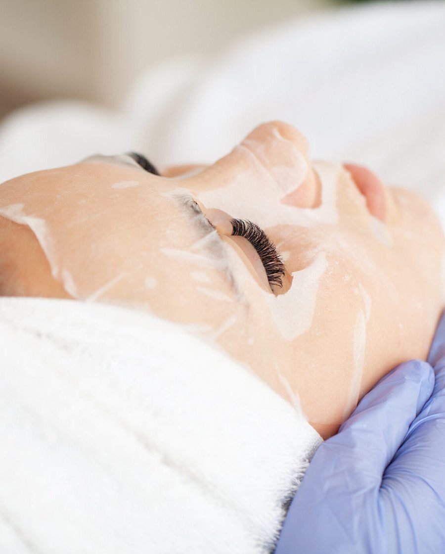 Young beautiful girl receiving facial mask in spa beauty salon.