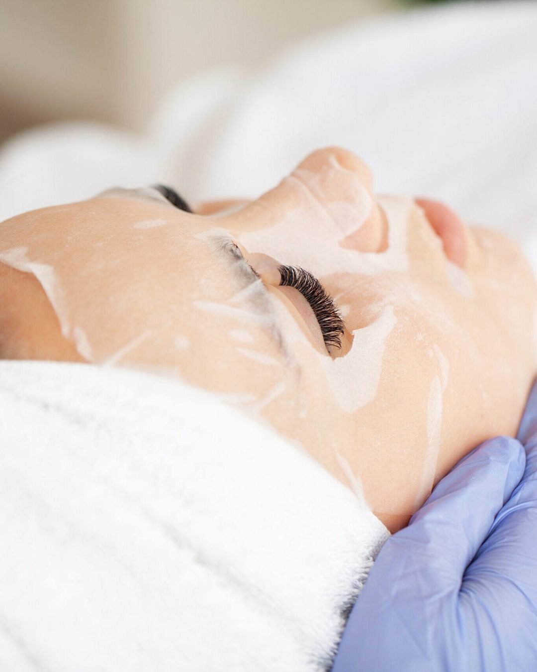 Young beautiful girl receiving facial mask in spa beauty salon.