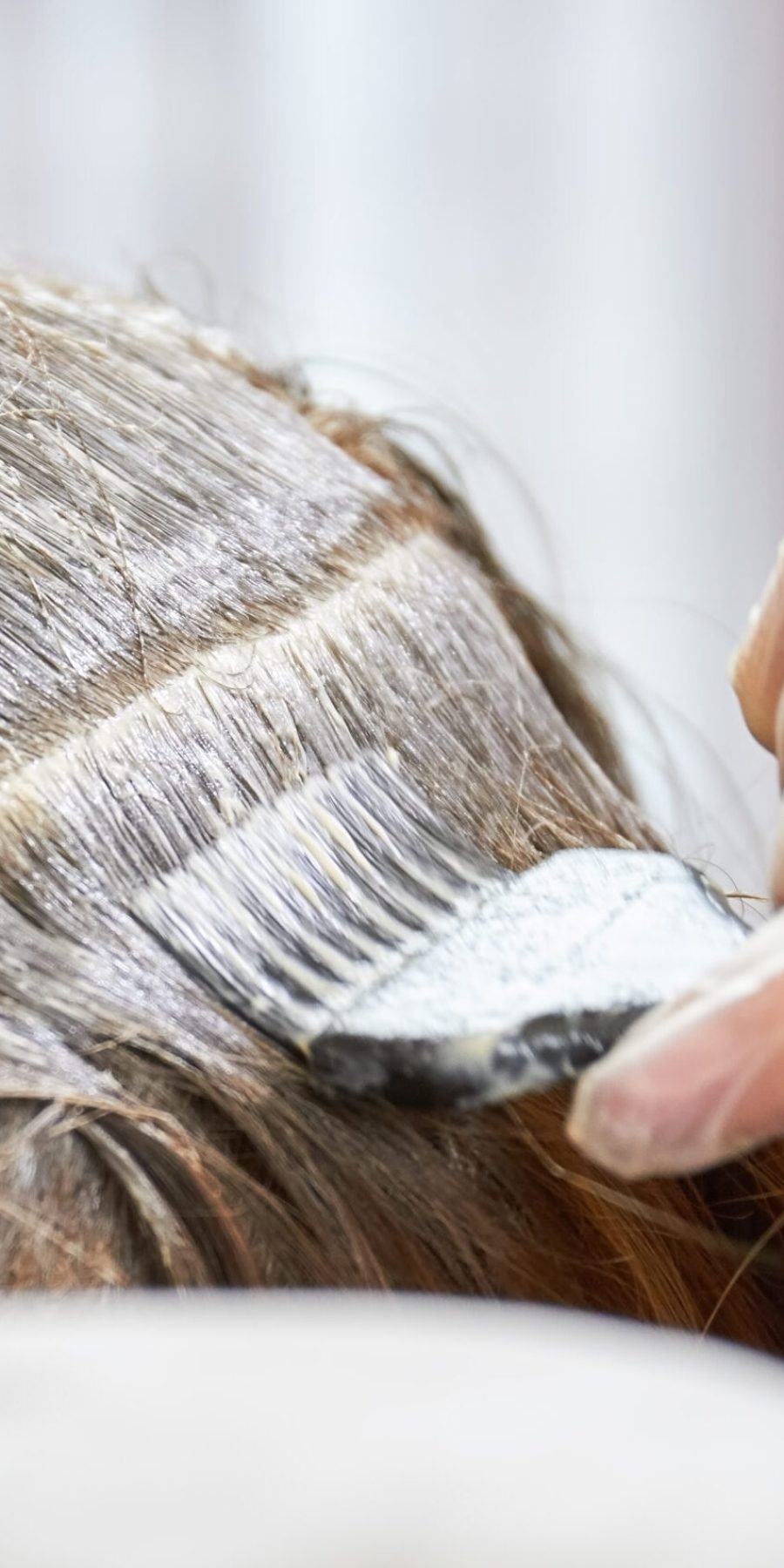 Hair dying process close up. Hand, brush and hair dye. Hair restore products.
