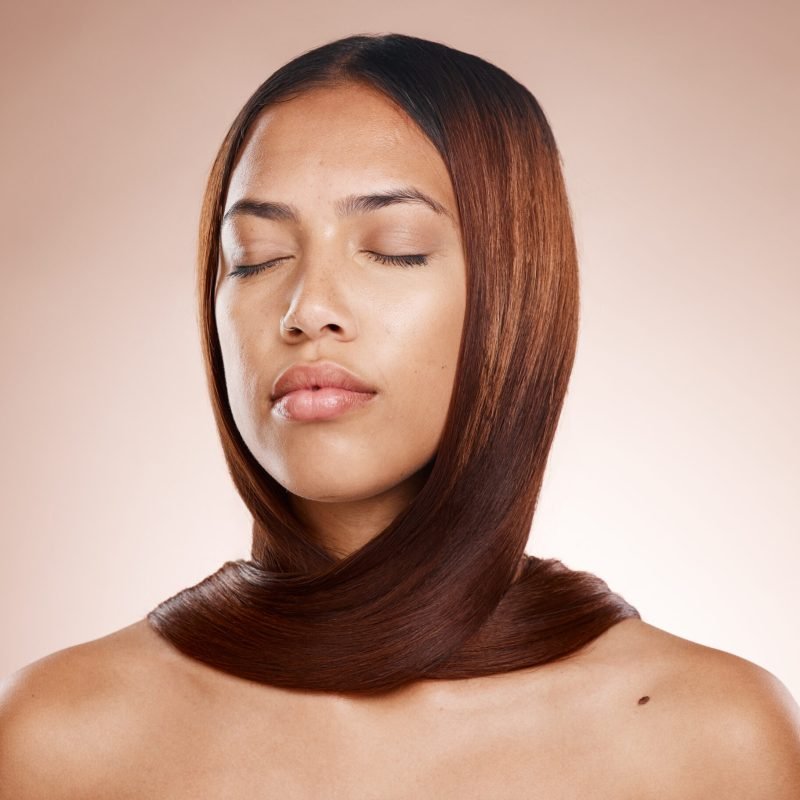 A woman with her eyes closed and hair styled in an updo, reflecting the effects of a keratin treatment.