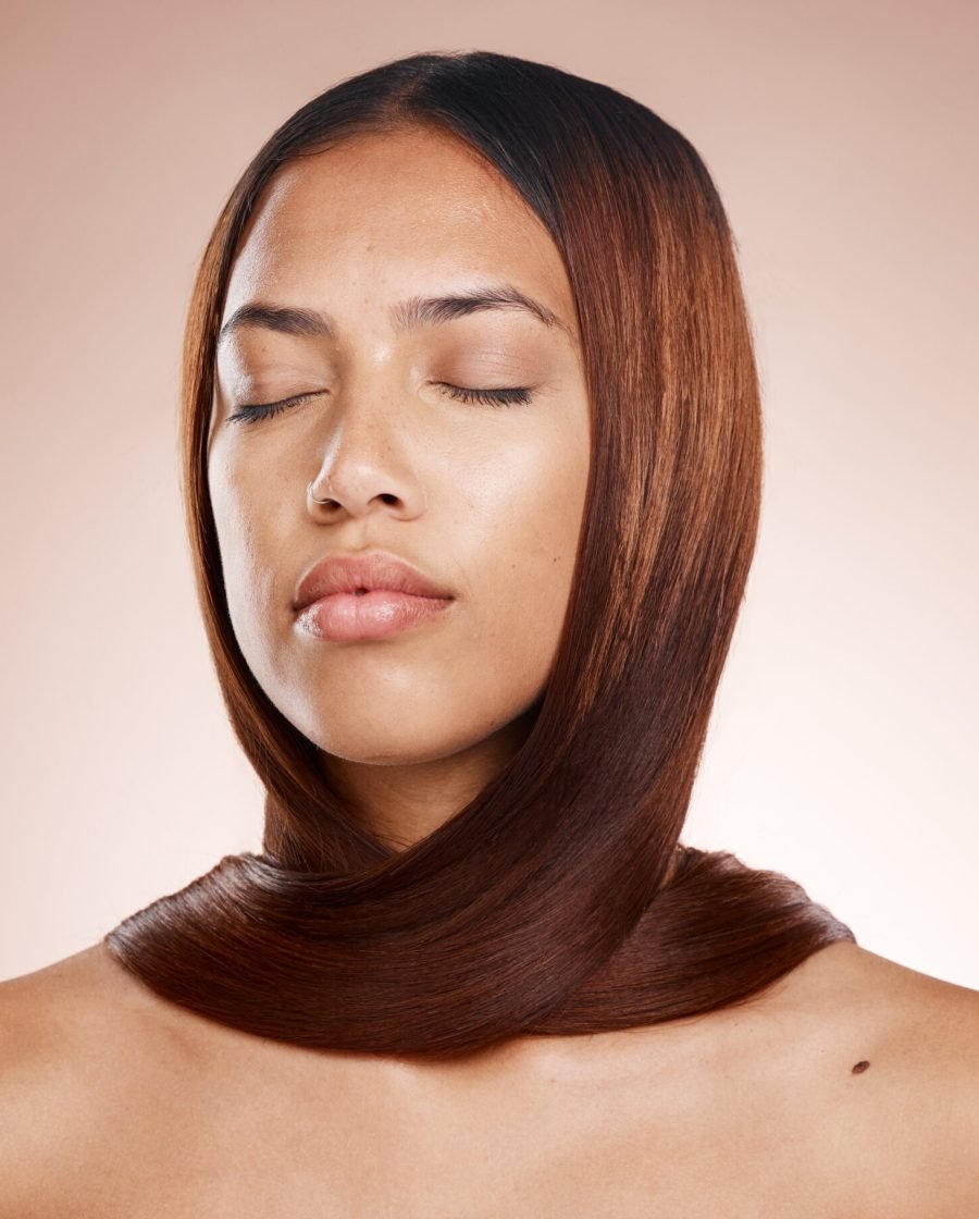 A woman with her eyes closed and hair styled in an updo, reflecting the effects of a keratin treatment.