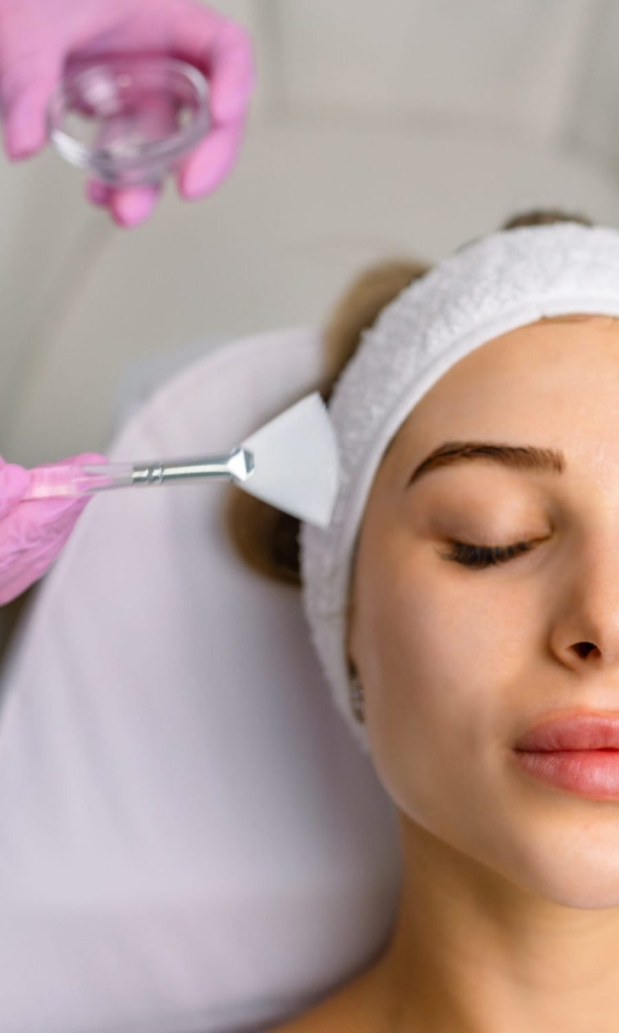 A woman receiving a skin brightening facial treatment in a beauty salon, in a relaxing mood.