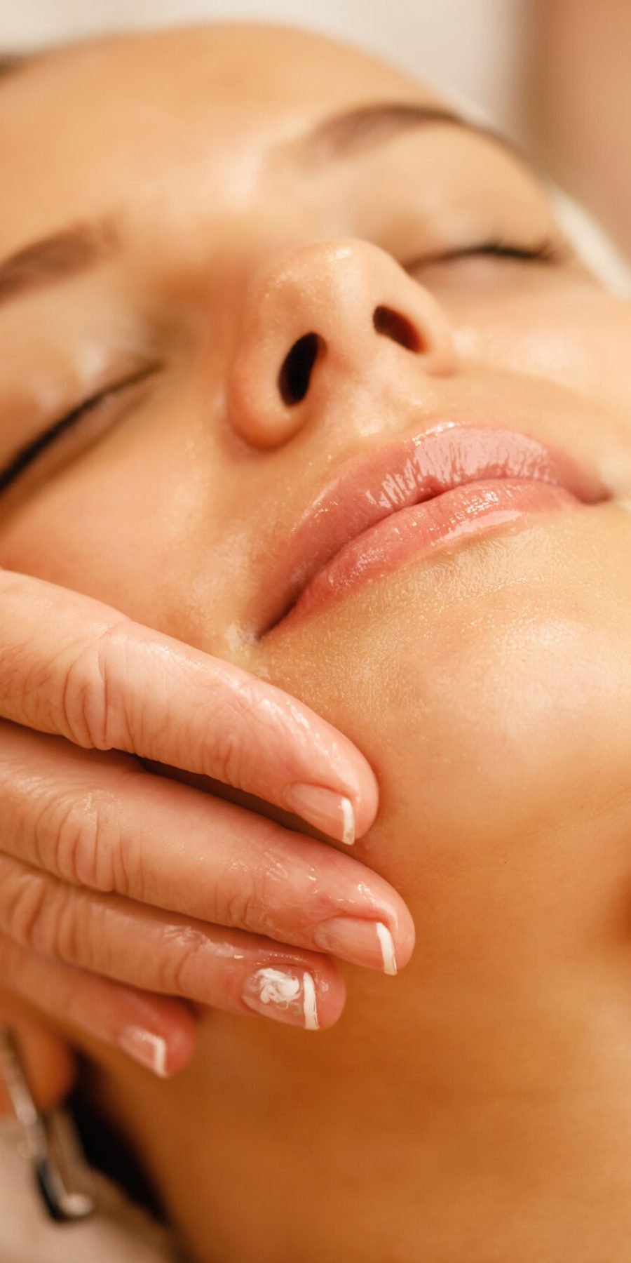A woman enjoys a soothing facial massage, enveloped in elegance and relaxation, embodying the essence of self-care.