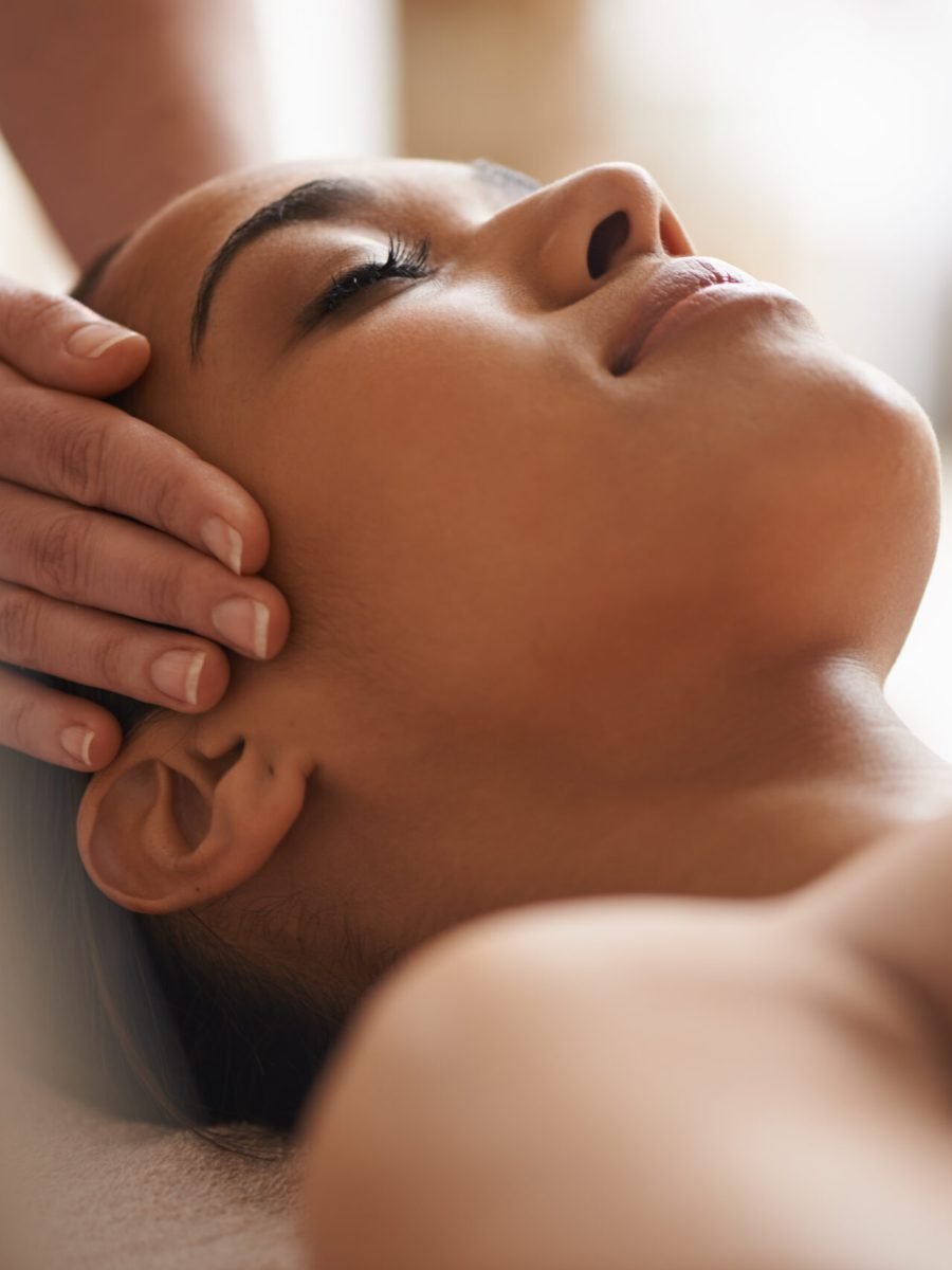 A woman enjoys a soothing facial and head massage at a tranquil spa setting.